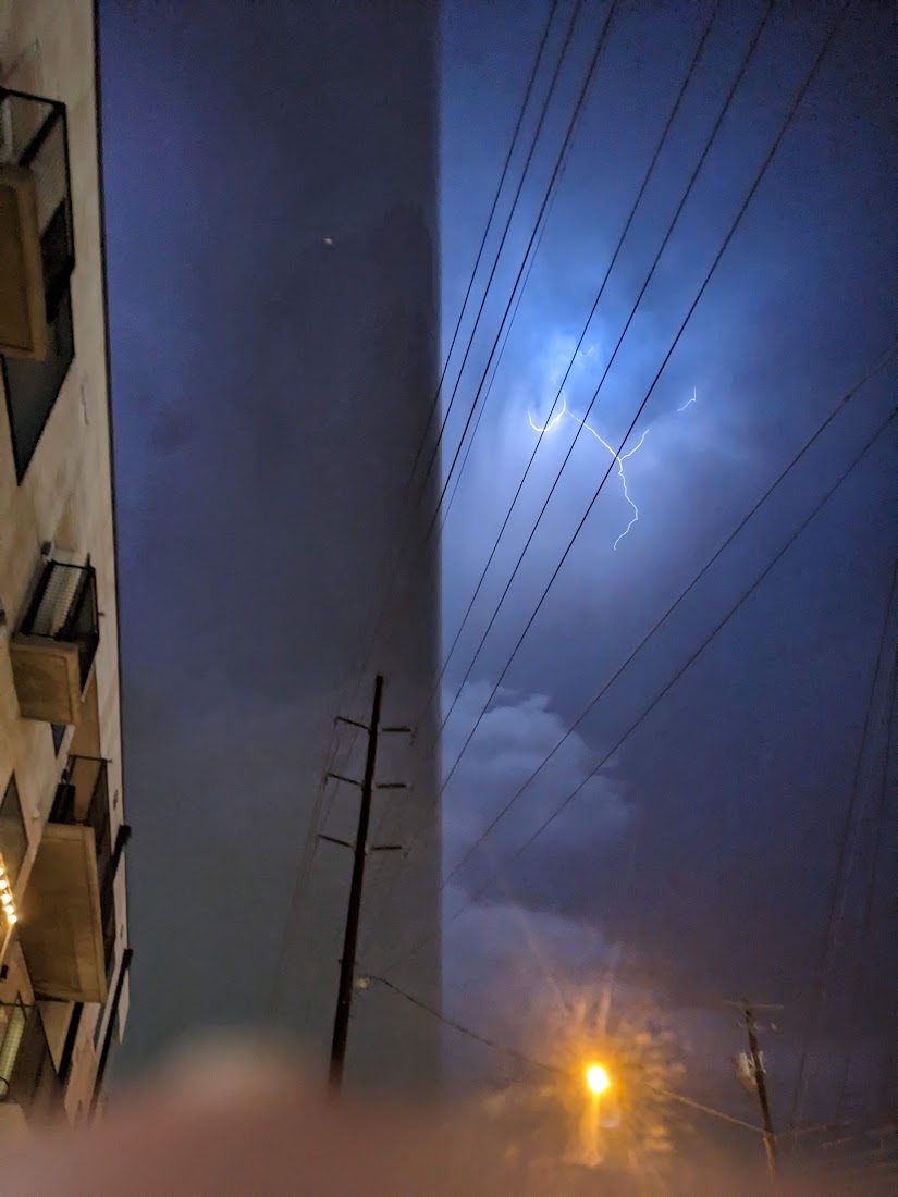 lightning striking. the timing is perfect such that half the night sky is illuminated by the bolt and half is not.